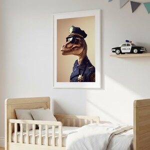 May include: A framed art print featuring a dinosaur in a police uniform and sunglasses. The artwork is displayed above a wooden toddler bed with a white comforter. A toy police car and books sit on a shelf.