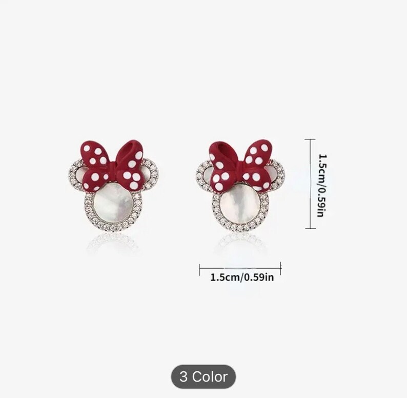 May include: A pair of red and white polka dot bow earrings with a white pearl center and a clear rhinestone halo. The earrings are 1.5 inches in diameter.
