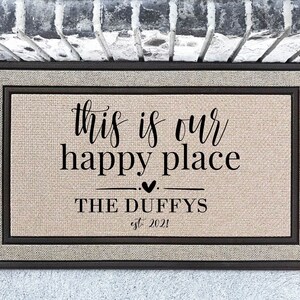 May include: A brown doormat with a beige background and black text that reads "This is our happy place THE DUFFYS est. 2021".