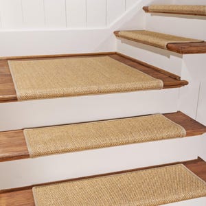 Peut inclure: Marches d'escalier rectangulaires fabriqu&eacute;es dans un mat&eacute;riau en fibres naturelles tiss&eacute;es de couleur beige. Chaque marche pr&eacute;sente un tissage serr&eacute; et textur&eacute;, avec une bordure en tissu beige assortie sur les bords, install&eacute;es sur des marches en bois.