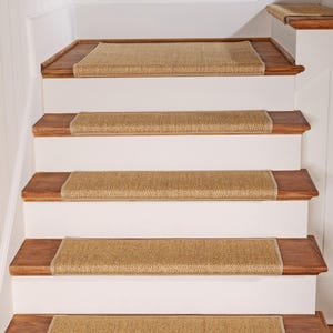 Peut inclure: Un ensemble de marches d'escalier rectangulaires en tissage beige avec des bords finis, install&eacute;es sur un escalier aux marches en bois brun fonc&eacute; et aux contremarches blanches. Les marches textur&eacute;es couvrent chaque marche de l'escalier.