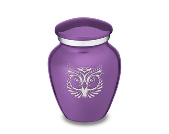 Puede incluir: Urna de cremación de metal morado con un diseño de búho grabado. La urna tiene una tapa plateada.