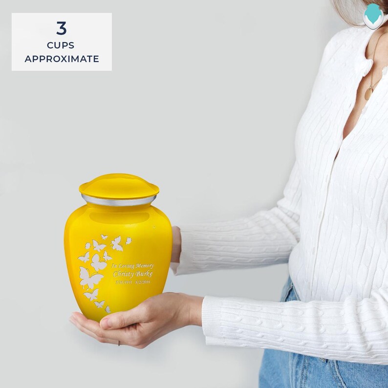 Puede incluir: Urna de cremaci&oacute;n de cer&aacute;mica amarilla con un dise&ntilde;o de mariposa y el texto "In Loving Memory Cherry Patty" en letras plateadas. La urna tiene una capacidad aproximada de 3 tazas.