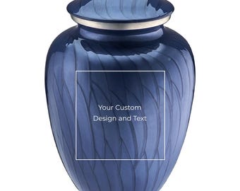 Puede incluir: Una urna de cremación de metal azul profundo con un acabado brillante y un patrón sutil de hojas grabado en la superficie. La urna cuenta con una tapa plateada y un marco rectangular central que contiene el texto Your Custom Design and Text.