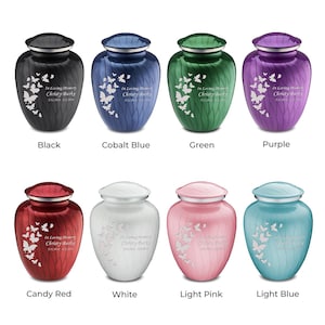May include: Ten cremation urns in various colors, including black, cobalt blue, green, purple, candy red, white, light pink, and light blue. Each urn features a butterfly design and the text "In Loving Memory Christy Burke".