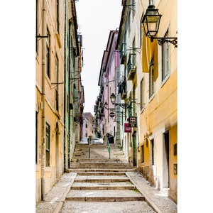 May include: A narrow, cobblestone street in a European city with colorful buildings on either side. The street leads up a set of stairs.