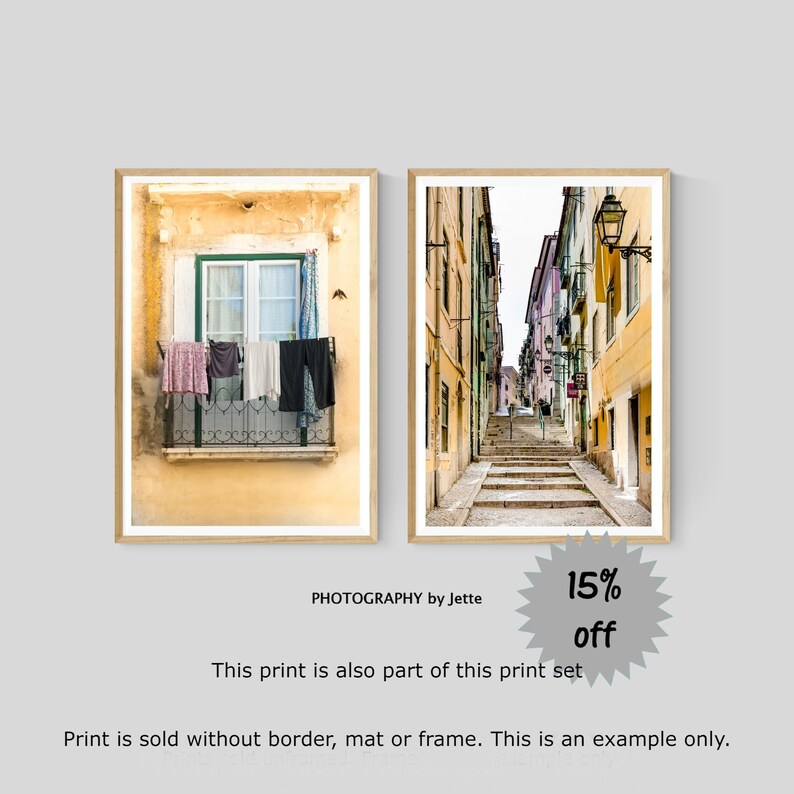 May include: Two framed photographs of a street scene in Portugal. The first photo shows a window with laundry hanging on a line. The second photo shows a narrow street with steps leading up to a building.