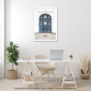 May include: A photograph of a blue door with a white archway and a white building behind it. The door has a number "24" above it.