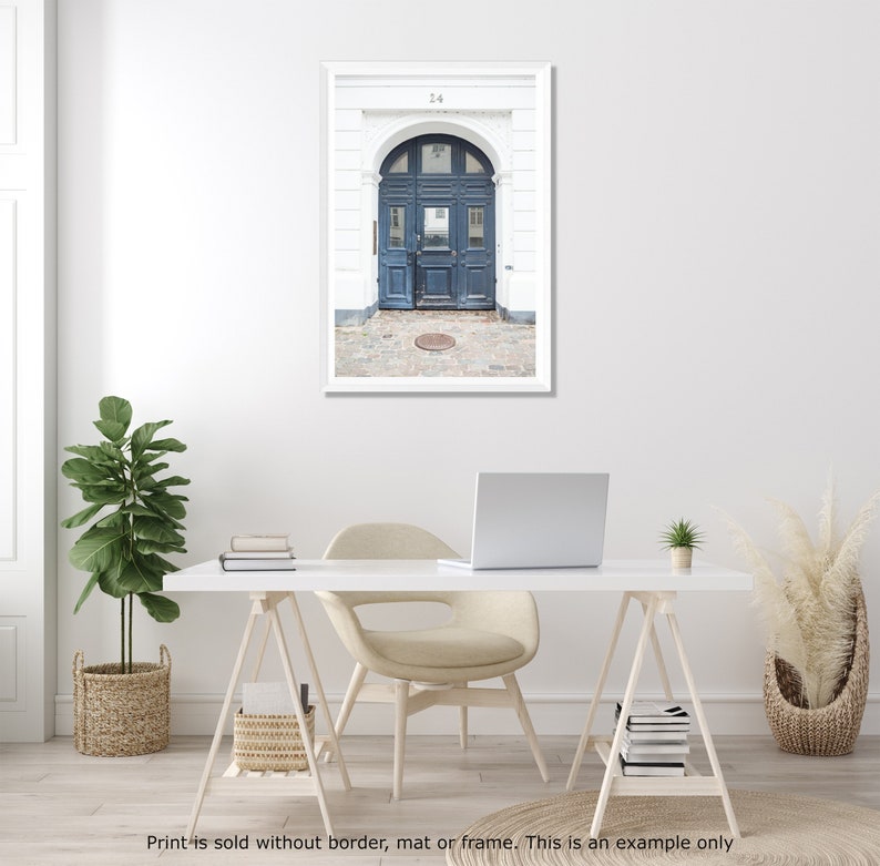 May include: A photograph of a blue door with a white archway and a white building behind it. The door has a number "24" above it.
