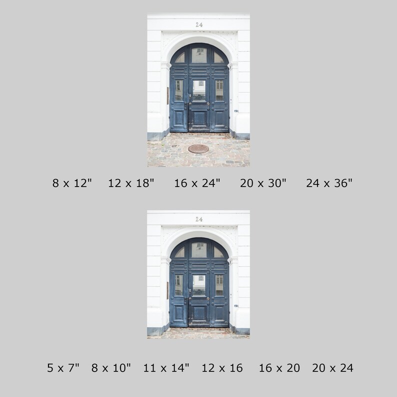 May include: A close-up of a dark blue wooden door with a decorative archway and white trim. The door has a small window in the center and a metal door handle. The door is set against a white brick wall.