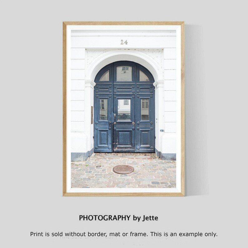 May include: A photograph of a blue wooden door with a white archway and the number "24" above it. The door is set in a white building with a brick walkway in front of it.