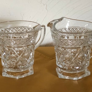 Peut inclure: Un ensemble vintage de pot à crème et sucrier en verre avec un motif en verre taillé. L'ensemble est transparent et a une base hexagonale.