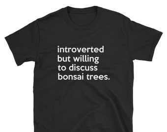 May include: Black t-shirt with white text that reads "introverted but willing to discuss bonsai trees." The shirt is made of a soft material and has a crew neck. The text is centered on the front of the shirt.