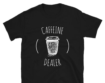 May include: Black t-shirt with a white graphic of a coffee cup and the words "CAFFEINE DEALER" in a handwritten style font. The design is centered on the front of the shirt.