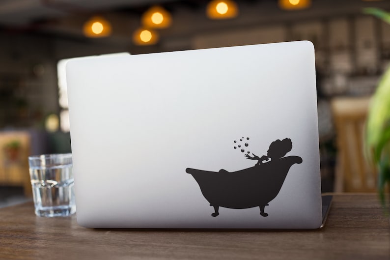 May include: A black silhouette of a person in a bathtub blowing bubbles on a silver laptop.