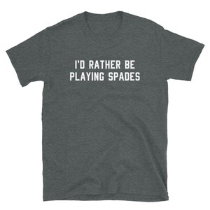 May include: Dark gray t-shirt with the white text "I'D RATHER BE PLAYING SPADES." The short-sleeved shirt is made of a soft material. The text is centered on the front of the shirt.