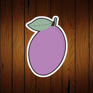May include: A sticker of a purple plum with a green leaf and stem. The plum is outlined in black and has a white border. The background is a wooden texture.