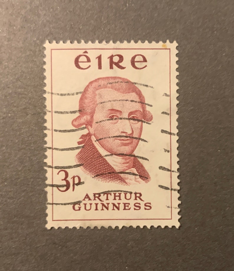 May include: A vintage Irish postage stamp featuring a portrait of Arthur Guinness, the founder of the famous brewery. The stamp is red and white and has the text "&eacute;ire" and "3p ARTHUR GUINNESS" printed on it.