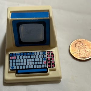 May include: A white plastic toy computer with a blue screen and keyboard. The keyboard has blue and pink keys.