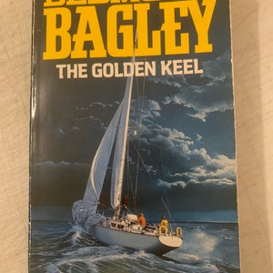 May include: A book cover featuring a sailboat on the water at night with a dark blue sky and white clouds. The title of the book is "The Golden Keel" by Desmond Bagley.