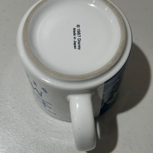 May include: White ceramic mug with a blue and white design. The mug has a handle and says "It's a Wonderful Life" on the front. The bottom of the mug says "&copy; 1987 Disney Made in Japan."