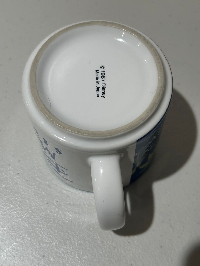May include: White ceramic mug with a blue and white design. The mug has a handle and says "It's a Wonderful Life" on the front. The bottom of the mug says "&copy; 1987 Disney Made in Japan."