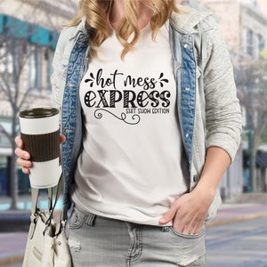 May include: White t-shirt with black text that reads "hot mess express shit show edition".