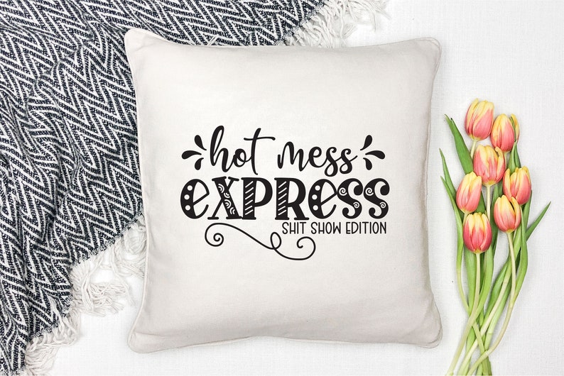 May include: White throw pillow with black text that reads "hot mess express" and "shit show edition".