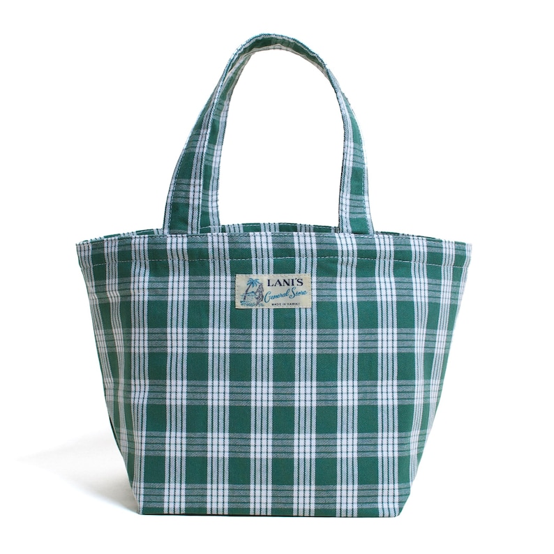 Op de afbeelding: Groene en witte geruite draagtas met korte handvatten. De tas heeft een rechthoekige vorm en een label met de tekst "Lani's General Store". De tas is gemaakt van een stevige stof en is geschikt voor het dragen van boodschappen of andere items.