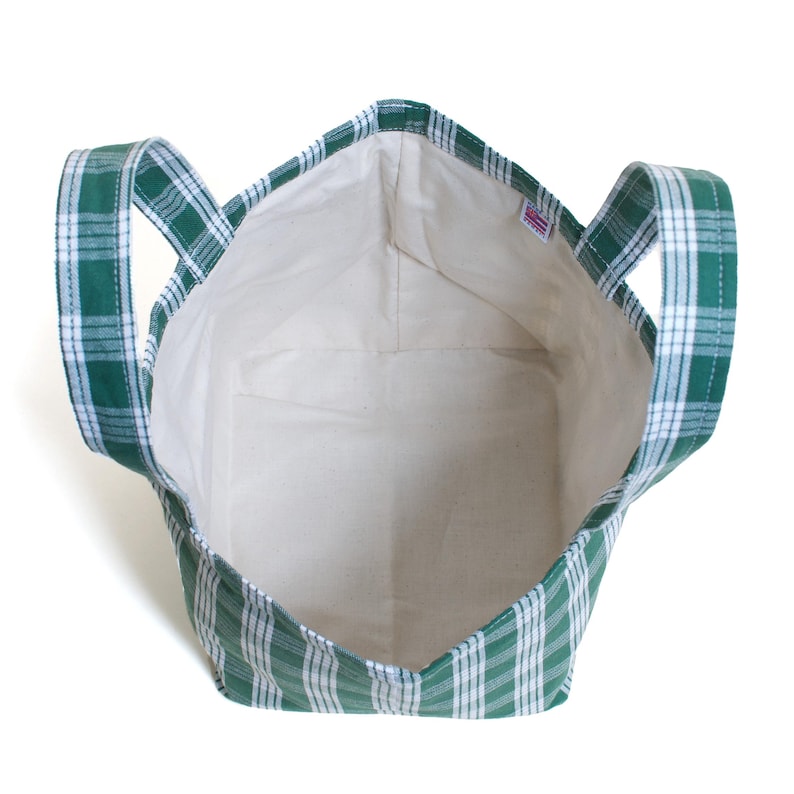 Op de afbeelding: Een groen-witte geruite draagtas met twee handvatten. De tas heeft een witte binnenkant en een rechthoekige vorm. Het geruite patroon is een klassiek ontwerp en de tas lijkt van stof te zijn.