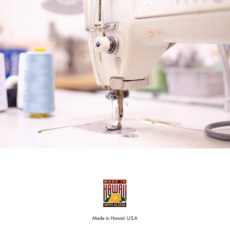 May include: Close-up of a white sewing machine with a spool of light blue thread. The machine is in use, with the needle going up and down. The text "Made in Hawaii with Aloha" is visible below the image.