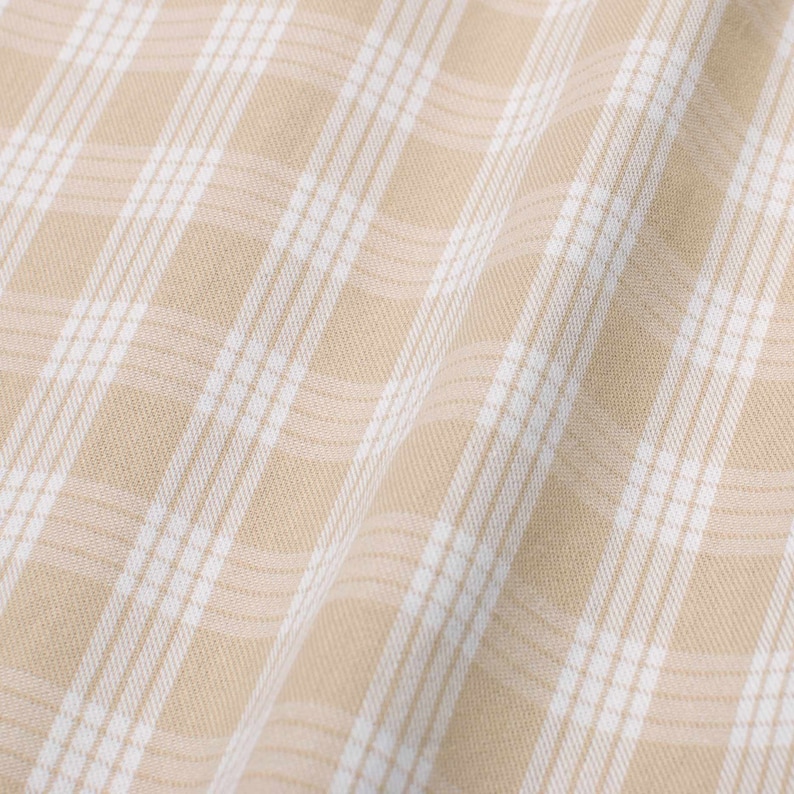 May include: Beige fabric with a white checkered pattern. The fabric is folded and has a soft, textured appearance.