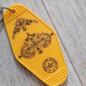 May include: Yellow plastic key chain with a black and white design that says "The Continental" and "The Ambassador Hotel".