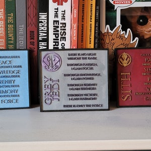 May include: Three wooden plaques with the words "Jedi", "Grey Jedi", and "Sith" on them. Each plaque has a symbol and a list of words associated with the respective faction. The Jedi plaque is blue, the Grey Jedi plaque is purple, and the Sith plaque is red.