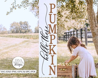 Könnte beinhalten: Ein weißes Holzschild mit den Worten "hello there PUMPKIN" in braunen Buchstaben. Ein junges Mädchen pflückt Äpfel aus einer Holzkiste vor dem Schild.