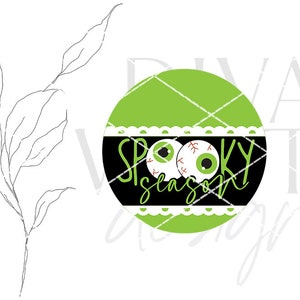 May include: A green and black circle with a white lace trim. The circle has two googly eyes and the text "Spooky Season" in black.