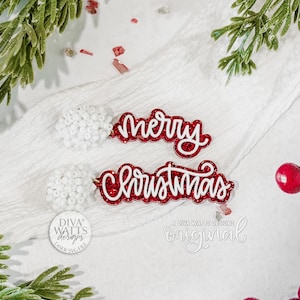 Op de afbeelding: Rode glitterende "Merry Christmas" uitsparingen met witte contouren, samen met witte kralenaccenten en takjes groen en rode bessen. De woorden zijn in een cursief lettertype. Het Diva Watts Designs logo is ook zichtbaar.