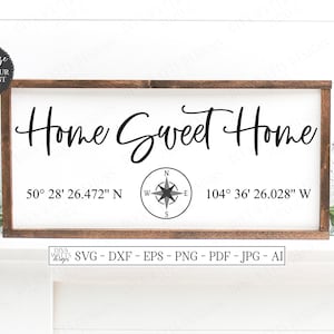 May include: A wooden sign with the text "Home Sweet Home" and coordinates "50° 28' 26.472" N 104° 36' 26.028" W" printed on it. A compass rose is in the centre of the sign.