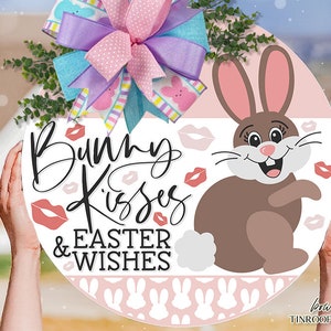 May include: A pink and white round sign with a brown bunny rabbit, pink lips, and the text "Bunny Kisses & Easter Wishes".