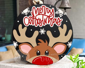 Puede incluir: Adorno de puerta navideño redondo negro con la cara de un reno y las palabras "Merry Christmas" en rojo y blanco. El reno tiene cuernos marrones, cara marrón, orejas rosas y nariz roja. Copos de nieve blancos dispersos.