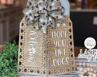 May include: Two wooden signs with a decorative cut-out border. The signs say "Welcome" and "Hope you like dogs". The signs are decorated with a brown and white bow with paw prints and bones.