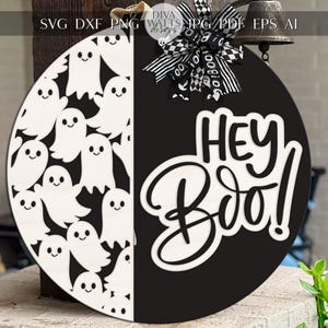 May include: A round, two-toned Halloween sign. The left side features white ghost cutouts, while the right side has the words "Hey Boo!" in white against a black background. A decorative bow and bell complete the festive design.