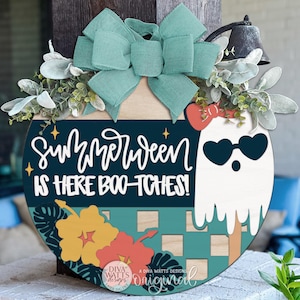 May include: Round wooden door hanger with a teal bow, greenery, and a ghost wearing heart-shaped sunglasses. The sign reads "Summerween is here boo-tches!" with floral accents. A fun, seasonal decoration.