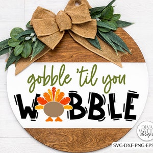 May include: A round wooden sign with a burlap bow and green leaves. The sign says "gobble 'til you wobble" in black lettering with a cartoon turkey in the middle.