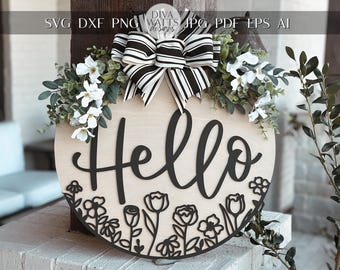 May include: A round wooden sign with the word "Hello" in black script lettering. The sign is decorated with black floral cutouts and a black and white bow.