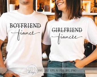 May include: Two white t-shirts with black text. The text on the left shirt says "Boyfriend" with a line through "friend" and "fiancé" written in cursive below. The text on the right shirt says "Girlfriend" with a line through "friend" and "fiancée" written in cursive below.