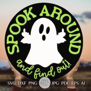 May include: A black circle with the text "Spook around and find out!" in green letters. A white ghost with two outstretched arms is in the center of the circle. The ghost has two eyes and a mouth.