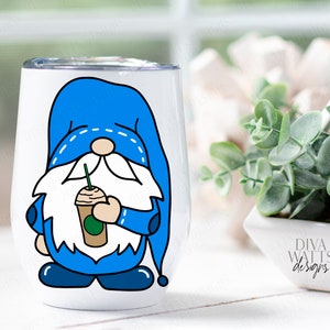 May include: A white stainless steel tumbler with a blue gnome holding a green and brown coffee cup. The gnome has a white beard and a blue hat with white stitching. The tumbler is on a white surface.