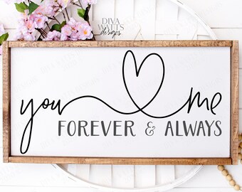May include: A white wooden sign with a brown frame, featuring the text "you & me forever & always" in black cursive script with a heart shape connecting the words.