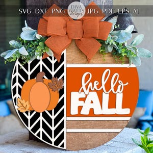 May include: A wooden fall-themed door hanger with a half-circle design. The design features a pumpkin and the words "hello FALL" in white. It is decorated with an orange bow and greenery. The background is a blurred outdoor scene.